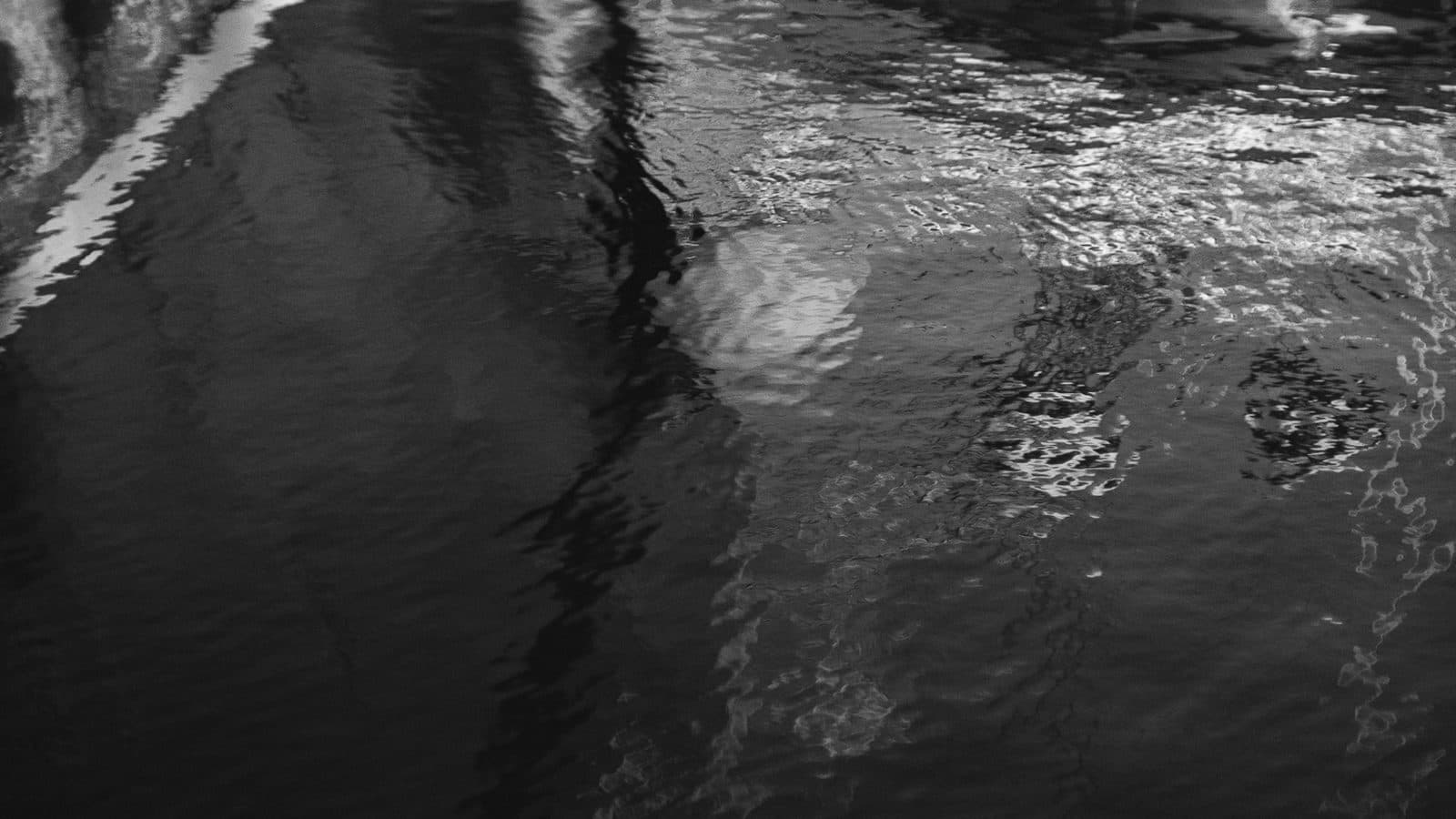 Black and white photograph of a boat hull reflected in Nantucket Harbor, taken by Owen Hudson